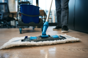 Operador treinado pela RL Higiene limpando o chão de uma empresa com ferramentas e produtos de limpeza profissionais, mop, balde, pessoa