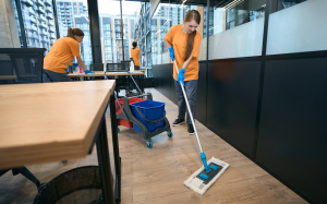 equipe de limpeza limpando uma area de coworking, mulher limpa chão, mulher limpa janela, mulher limpa móveis, limpeza profissional com redução nos custos