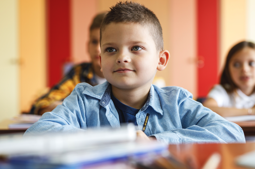 No ambiente focado da sala de aula, um estudante menino criança se concentra em seu teste, determinado a mostrar seu conhecimento e se destacar academicamente sob a orientação de seu professor atencioso.